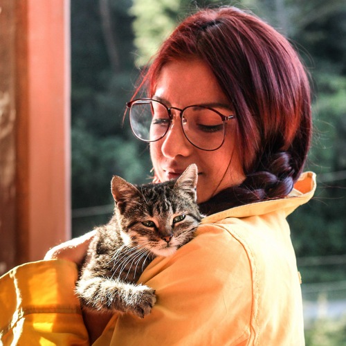 lifestyle image of a young woman holding a cat